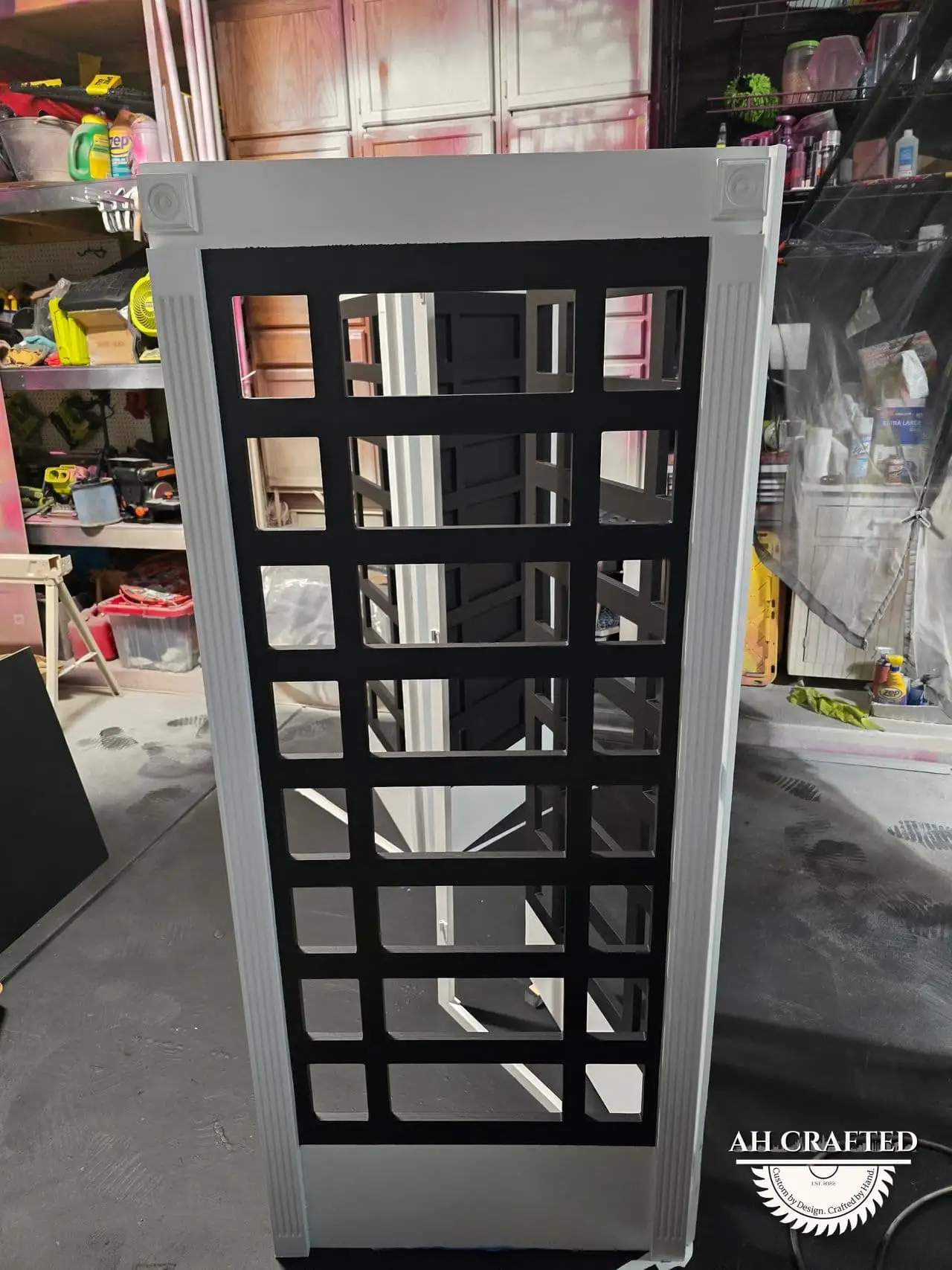 A side panel painted white with black lattice panes, drying in the shop.