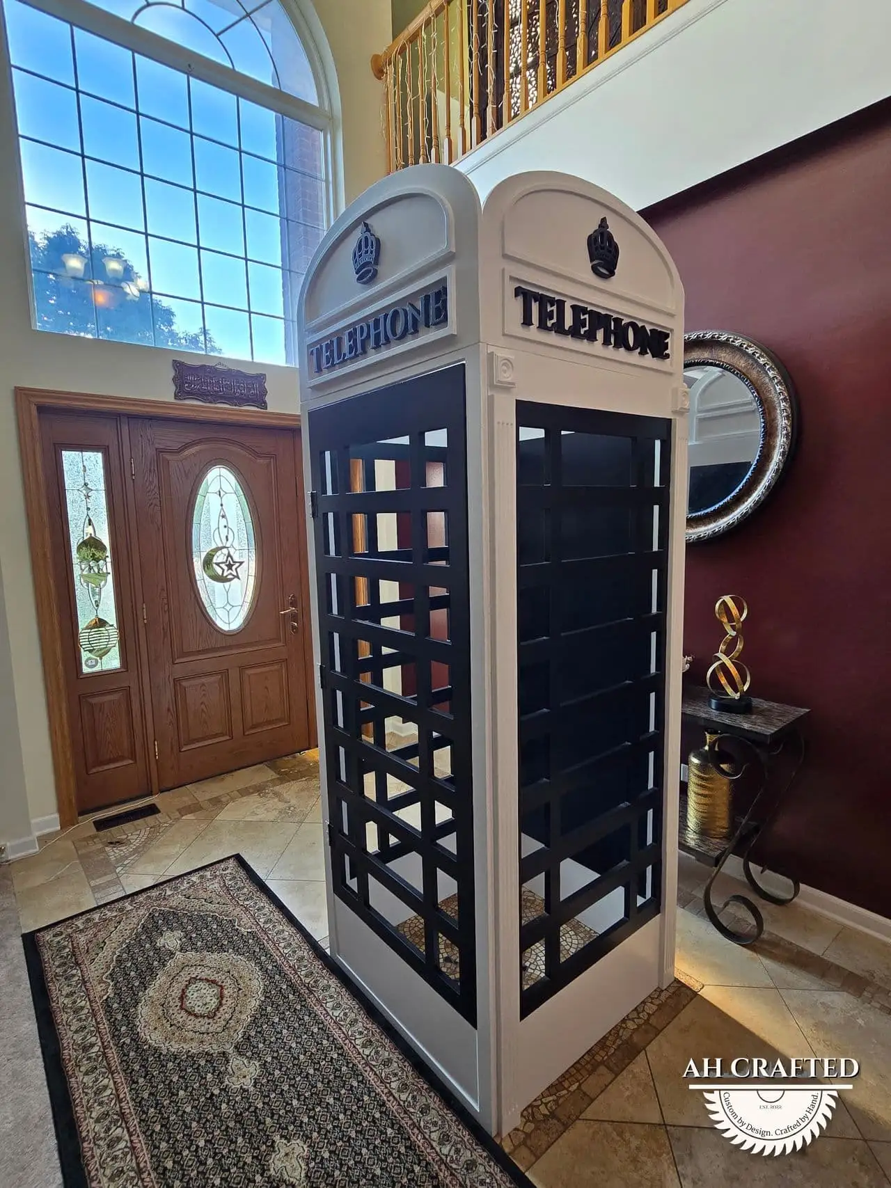 The finished booth installed in a two-story foyer, reflected in the entry glass.